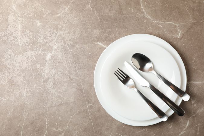 Plates with cutlery on gray background, top view