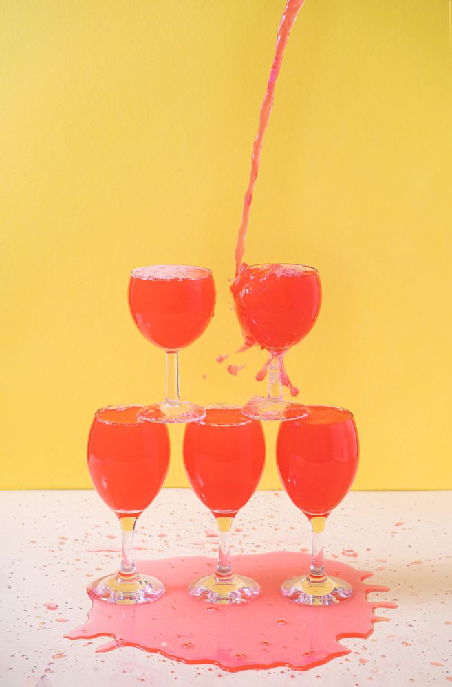 Rose liquid pouring and pilling into stacked wine glasses