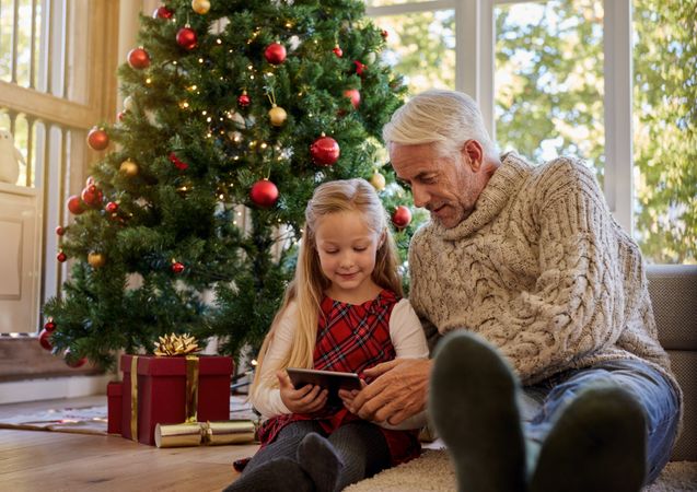Senior man with granddaughter using digital tablet during christmas