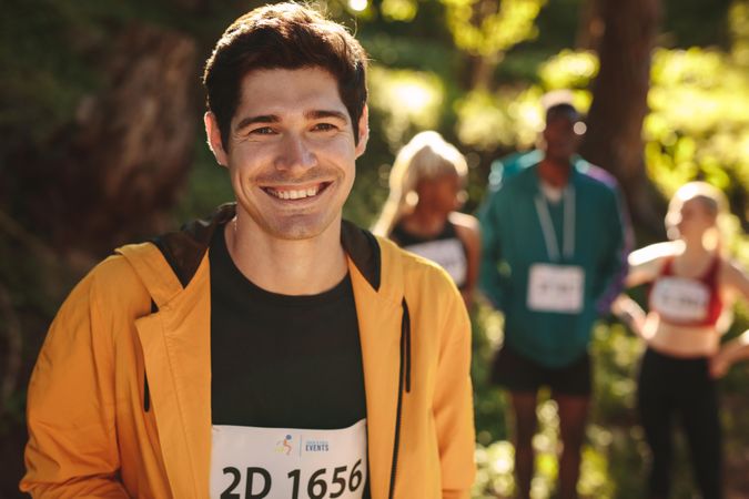 Male runner standing outdoors looking at camera and smiling
