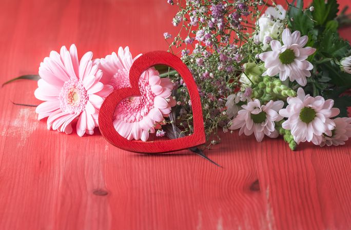 Decorative heart on pink flowers on rustic red table