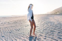 Woman touching hair on beach in oversized shirt