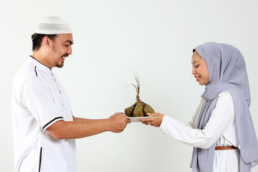Asian Muslim Female and Male Holding Plate with Ketupat for Eid Mubarak Celebration