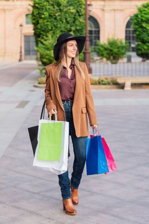 Content female in trendy wear doing shopping at city street