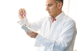 Assistant working in lab with pink liquid