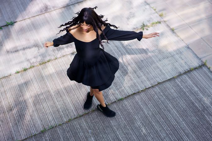 Elegant woman dancing in circles raising hands in the street