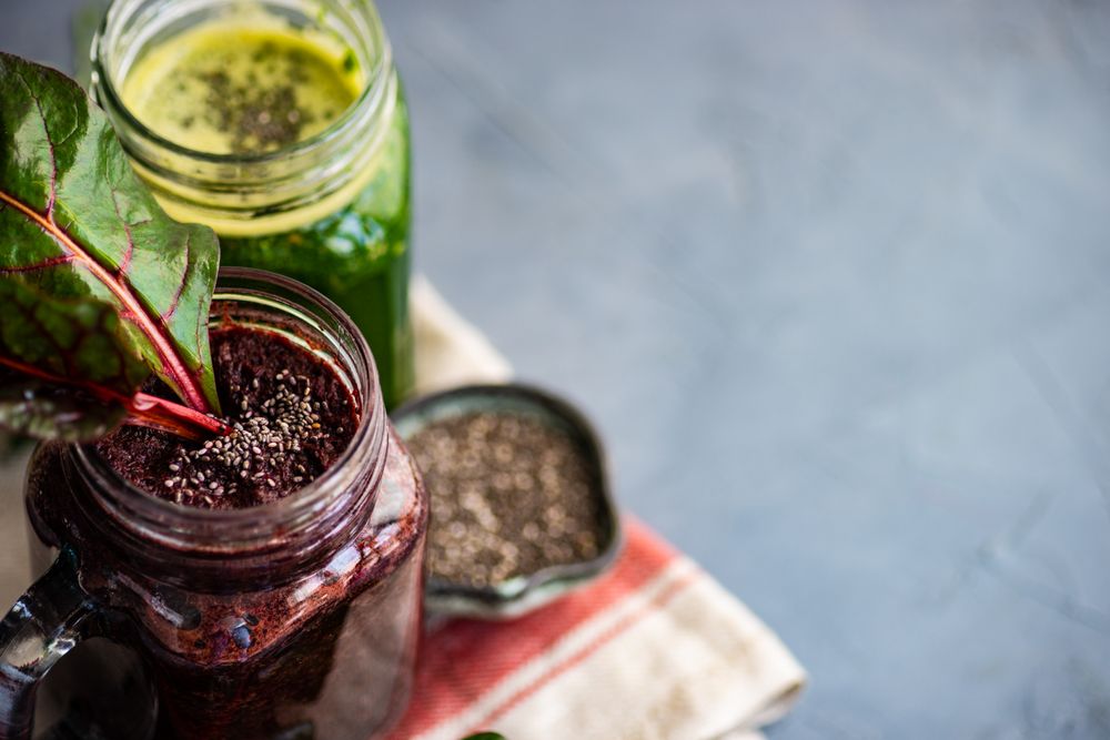 Beet and green smoothies on grey counter