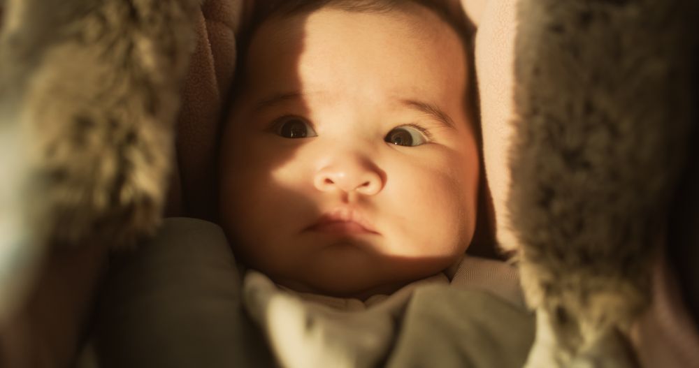 Portrait of a Cute Asian Baby Resting in a Crib, Surrounded by a Soft Blanket.