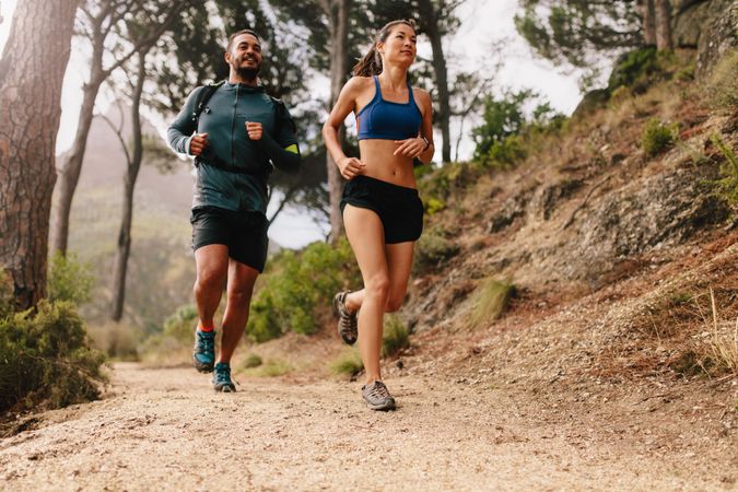 Fit couple running on mountain trail in morning