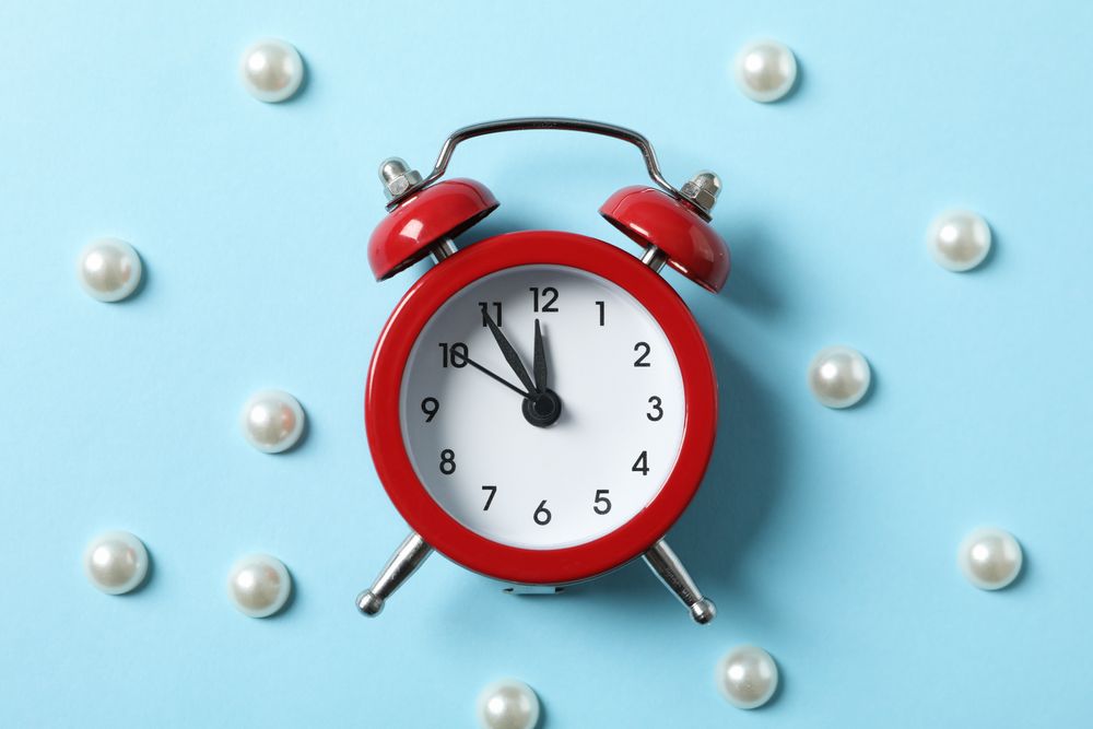 Alarm clock and beads on blue background. Happy new year