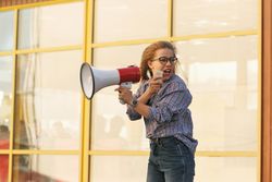 Woman yelling into megaphone in checkered shirt