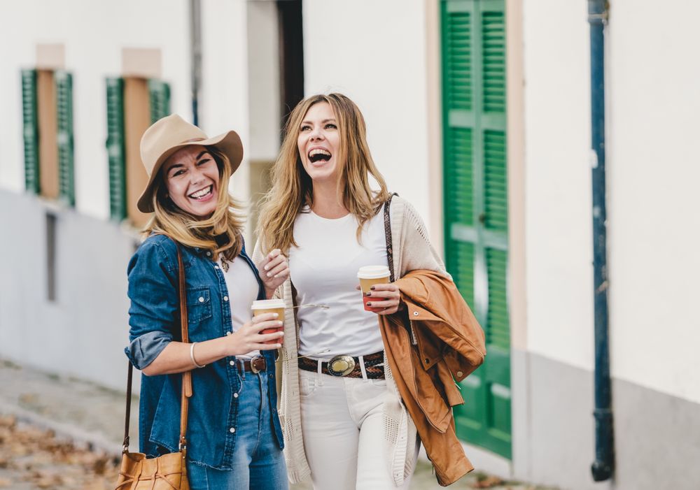 Women walking and chatting with cups of coffee