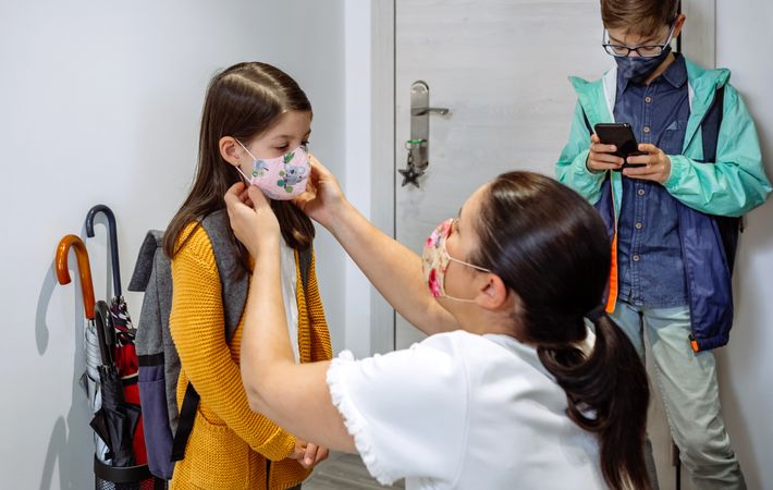 Mother putting the mask on her daughter