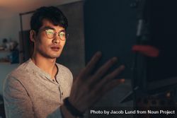 Handsome Korean man in glasses looking at glowing screen 4mdmW5