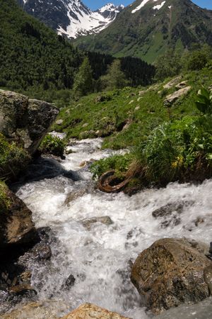 Mountain stream surrounded and rocky terrain with snow-capped peaks