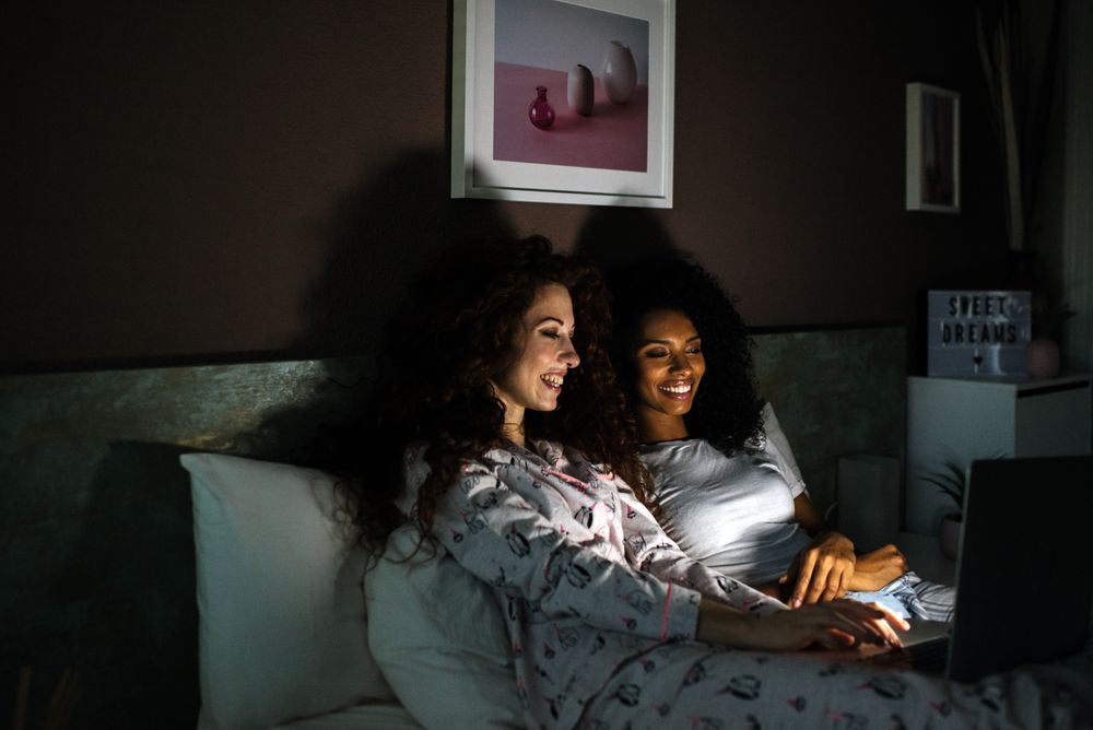 friends in bed entertained on their computer