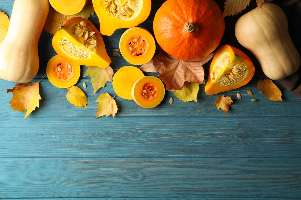 Composition with pumpkin, squash, seeds and leaves on wooden background