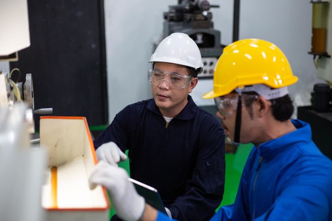 Two Asian males working together with heavy machinery