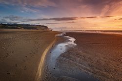 Tide going out on quiet beach at sunset