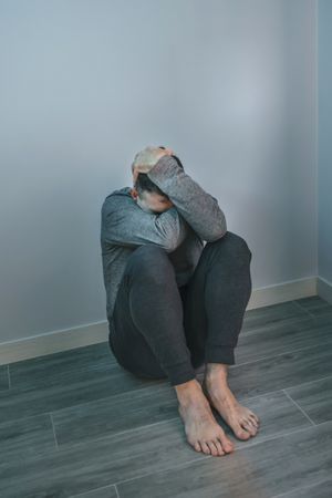 Unrecognizable man with problems sitting on floor