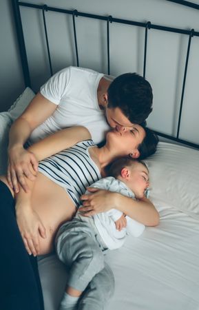 Pregnant woman kissing her partner with their son