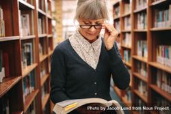 Woman standing in a library holding a book 5rqm20