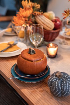 Soup in ceramic pumpkin shaped bowl on dinner table