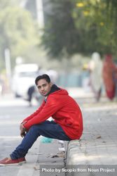 Man in red hoodie sitting on sidewalk 4mKJo0