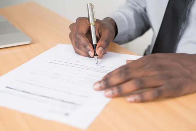 Cropped image of Black man writing on paper on his desk