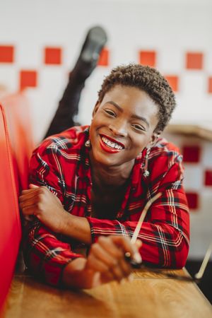 Gorgeous stylish Black woman lying on seats in cafe