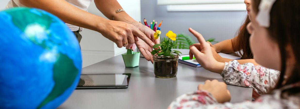 Teacher and young students pointing to pansy plant in ecology classroom