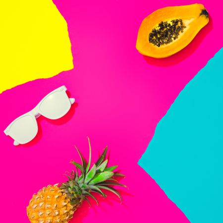 Pineapple, papaya and sunglasses on pattern of ripped paper in vivid colors