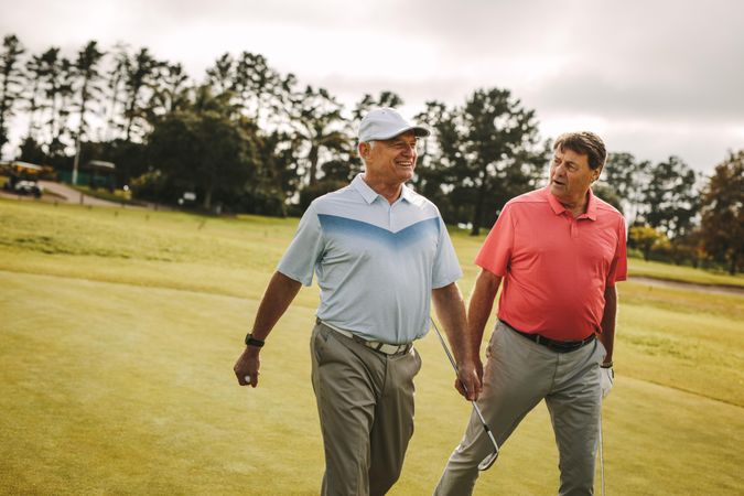 Two older men playing golf walking to the next hole
