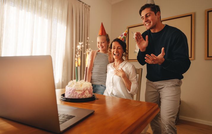 Woman celebrating birthday at home with family and friends on video call