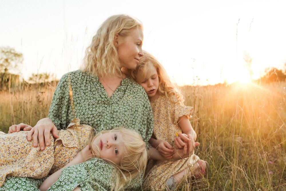 Calm mother embracing daughters in sunlight