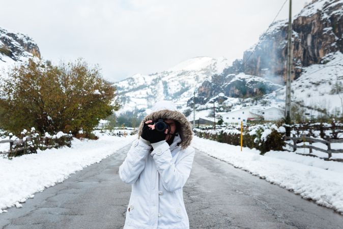 Content woman taking picture in snowy mountains