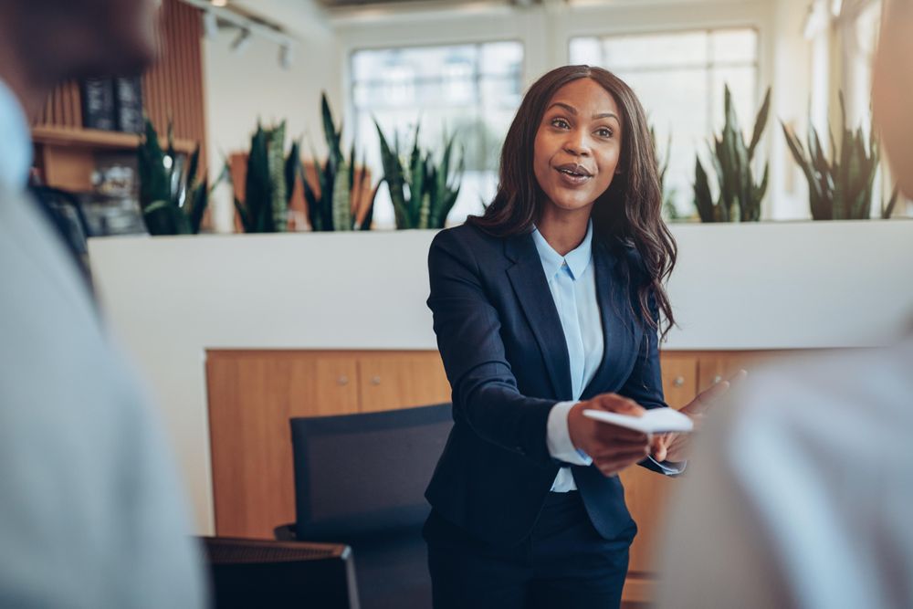 Woman speaking while sharing a note with people at the front desk