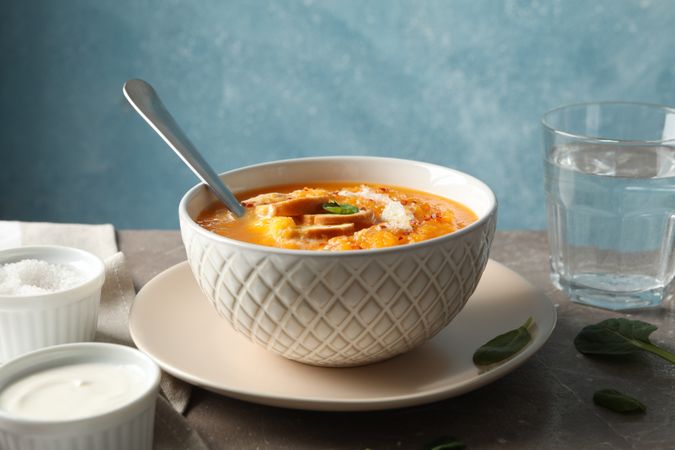 Bowl of delicious pumpkin soup on table with glass of water