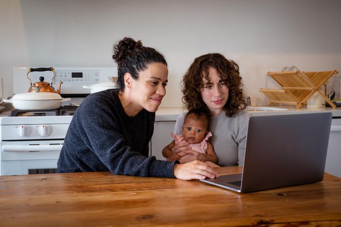 Two woman on laptop at kitchen table with baby