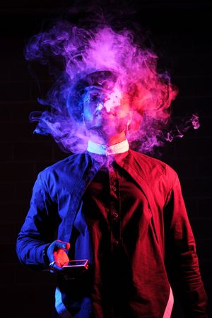 Black man exhaling smoke on dark background