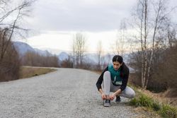 Young woman tying her shoe laces during a running break