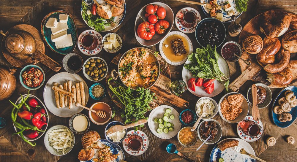 Bountiful table of fresh breads, eggs, vegetables, tea pots at traditional Turkish breakfast