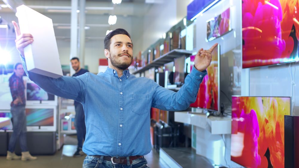 Young Man in Electronics Store Purchased Latest Model of the Tablet Computer and Dances Happily with the Box.