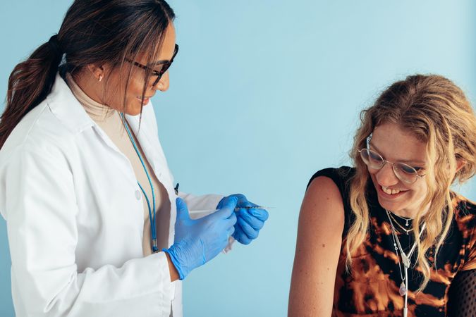 Smiling young woman getting vaccine from a female doctor