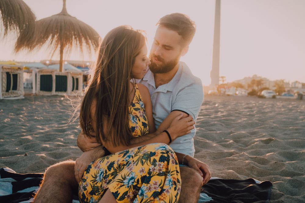 Tender couple embracing and kissing in sunlight on beach
