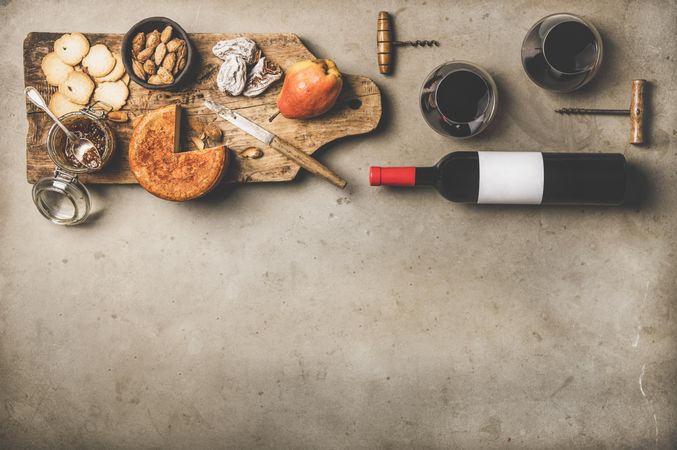 Cheese plate with red bottle of wine on linen towel, cork screws, with copy space