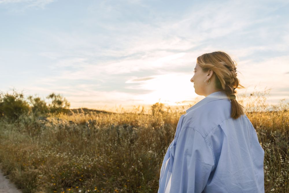 side view of a blonde woman portrait on a field during sunset