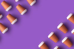 Disposable coffee cups in the corners on purple background