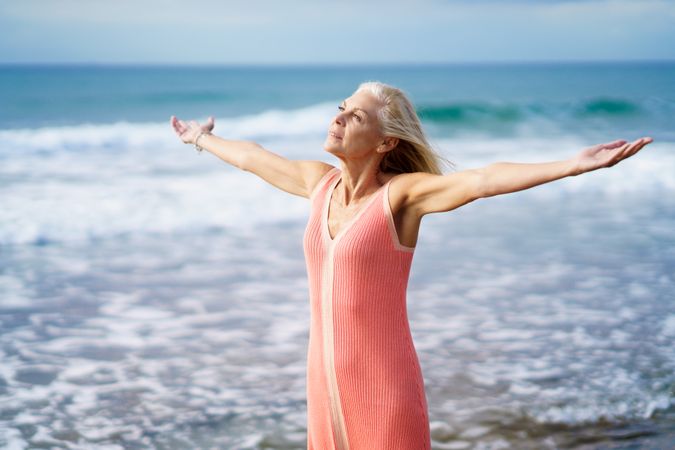 Older woman with arms outstretched on the coast