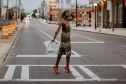 Black woman in red heels holding a newspaper walking across the crosswalk 41rQpb